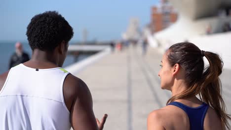 Athletic-young-couple-jogging-along-embankment